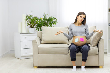 Photo of pregnant woman holding a paper with gender of the child.