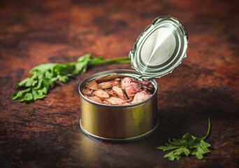 Canned octopus open on a dark blue table with parsley Ready for eat. 