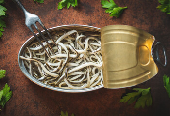 Canned baby eels open on a dark blue table with a fork and parsley. Ready for eat. 