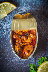 Canned scallops with sauce open on a dark blue table with lemon and parsley. Ready for eat. 