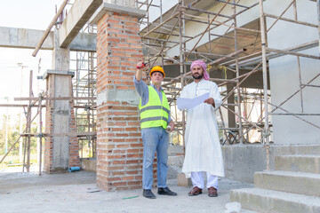 Fototapeta premium Arabic businessman teammates working together, construction engineer architect and worker looking building model and blueprint blueprint plans of Arab businessman.