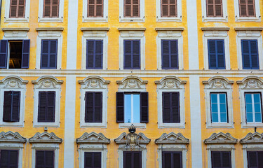 Fototapeta na wymiar Several rows of windows on the facade of an elegant residential building in the historical centre of Rome, Italy, useful as a background.