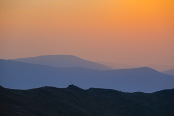 mountain chain silhouette in blue mist at the sunset, early morning mountain travel scene