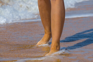 closeup woman legs on sandy sea beach, summer sea vacation scene