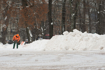 Workman with shovel at work in winter clearing snow in the square after a snowstorm in Vilnius,...
