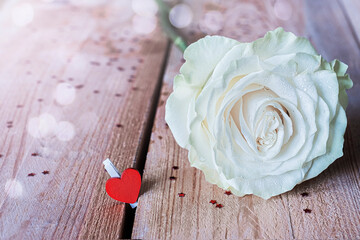 White rose with red heart on wooden table background