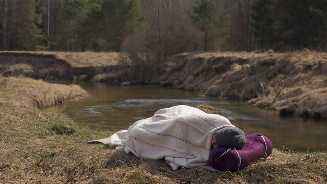 Tourist sleeps on the bank of the river