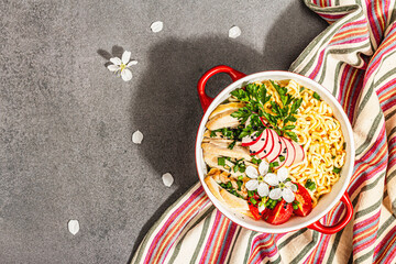 Asian noodles with chicken, vegetables, and herbs in a red bowl. Traditional Japanese soup