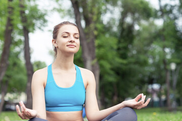 Girl meditates in lotus pose on green grass