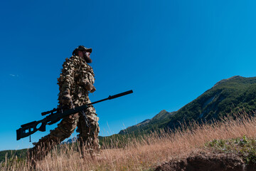 Army soldier holding a sniper rifle with scope and walking in the forest. war, army, technology and...