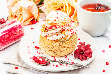 The concept of romantic tea. French Shu cake, hibiscus tea, bouquet of roses, festive decor