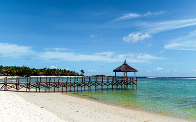 Idillic wood pier in a beach. tropical green area amazing calm mood. White sand and turquise color water.
