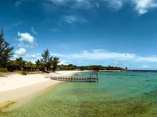 Idillic wood pier in a beach. tropical green area amazing calm mood. White sand and turquise color water.