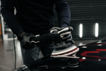 Obraz premium A man cleans a car and dries the interior with a polishing tool Manual car cleaning. Car detailing and car wash concept.