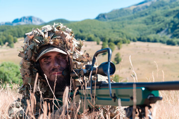 Army soldier holding sniper rifle with scope and aiming in forest. War, army, technology and people...