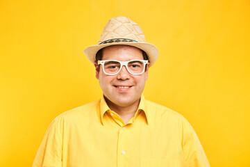 Portrait of positive fat man in hat kindly smiling isolated on yellow studio background, travel vacation concept