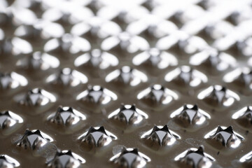Dramatic macro view of the holes in a kitchen grater. Narrow depth of field, focus below