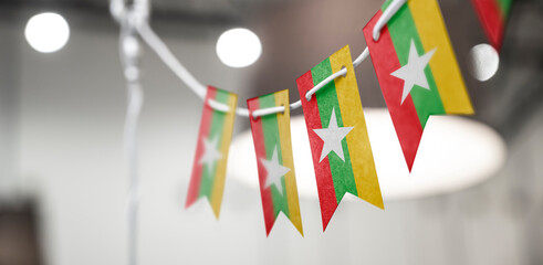 A garland of Myanmar national flags on an abstract blurred background