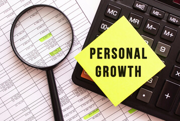 A colored sticker with the text PERSONAL GROWTH lies on the calculator. Financial concept.