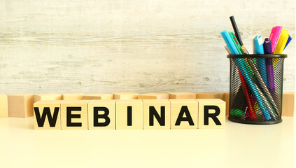 Seven stacked wooden cubes with letters WEBINAR on a white work table on a gray background.