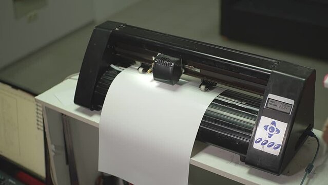 the cutting plotter cuts out the inscription on a white A4 sheet. High-quality Full HD video recording. live video