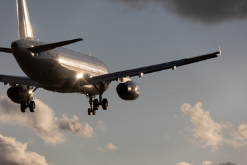 close-up of a silver aircraft in final approach at Stuttgart Airport, against bright cloudy sky....