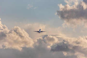 Aircraft taking off at Stuttgart Airport, against bright cloudy sky. The silver aircraft ist...