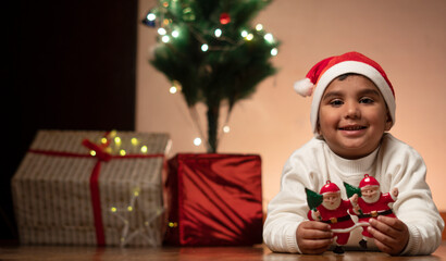 Fototapeta na wymiar child boy with christmas tree wearing santa cap 
