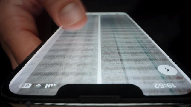 A Man in The Dark Quickly Flips Through Posts on Social Networks. The Concept Phone Is Always in Your Hand. Close up