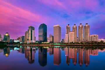 Fototapeta premium Skyline of highrises reflecting in lake waters at sunset. Bangkok