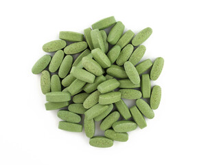 Green oval shaped pills on a white background. Tablets large spirulina. Food supplement in the form of tablets top view.