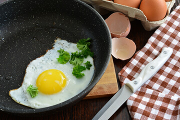 fried egg with yellow yolk on frying pan isolated with plaid kitchen napkin and egg shell