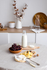 breakfast on the kitchen table with milk, cheese, grapes and nuts, Scandinavian kitchen interior with wooden plates