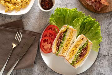 Top view of classic sandwiches stuff with ham, bacon and scrambled eggs for breakfast