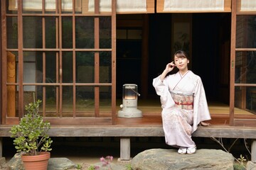 古民家の縁側でポーズをとる着物を着た若い女性