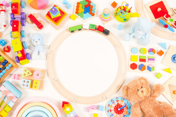 Fototapeta na wymiar Baby kids toys frame background. Teddy bear, wooden educational, musical, sensory, sorting and stacking toys, wooden train, rainbow, colorful building blocks on white background. Top view, flat lay