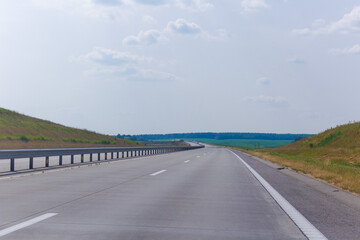 Fototapeta premium Highway wide road, transport and blue sky with clouds on a summer day
