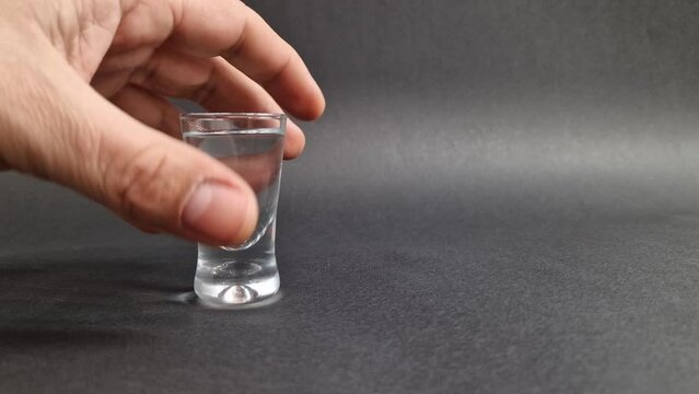 Alcoholic man with shaking hand drinks shot glass of vodka alcohol. Addiction to alcohol concept