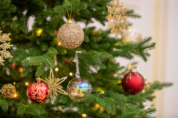 Christmas tree and Christmas decorations. Beautifully decorated Christmas tree on a blurred background, close-up of balls on the Christmas tree, bokeh garlands in the background, New Year. 2023.