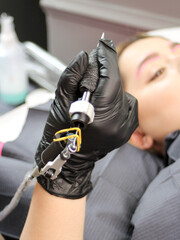 Cosmetologist applying permanent make up eyebrows for a client in a salon.Microblading
