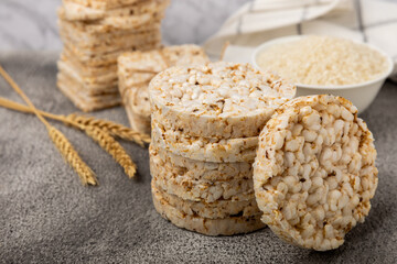 Rice cakes on a black texture table, against the background of a plate of rice. Close-up. Healthy food. Diet food.