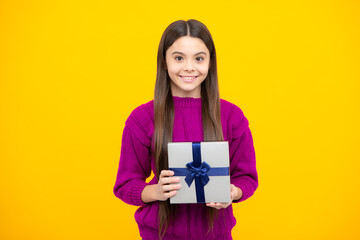 Young teenager girl child holding gift box isolated on yellow background. Gift for kids birthday.