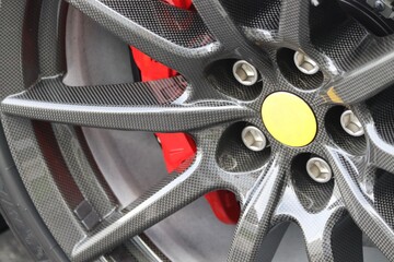 Closeup of a sports car wheel/ Precision engineering on display/ Red brake caliper adds a touch of...