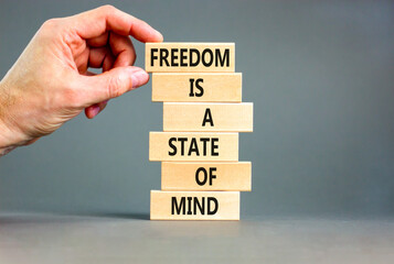 Freedom in mind symbol. Concept words Freedom is a state of mind on wooden blocks on a beautiful grey table grey background. Businessman hand. Business freedom is a state of mind concept.