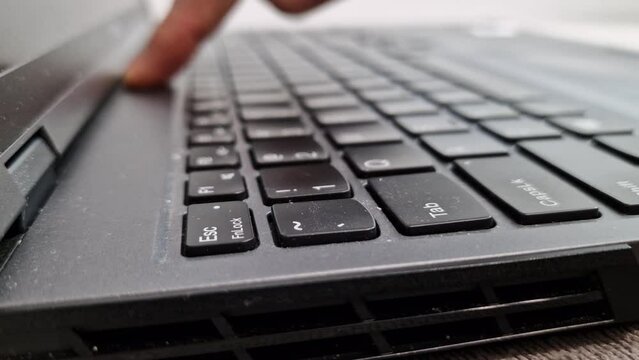 Man is cleaning his dirty laptop computer with his fingers. Care for computer equipment