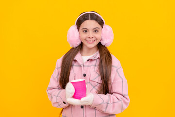 glad child in earmuffs with coffee or tea cup on yellow background, morning