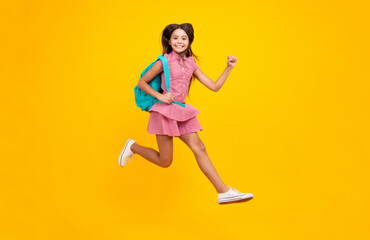 Fototapeta na wymiar School girl in school uniform with school bag. Crazy run and jump. Schoolchild teenager hold backpack on yellow isolated background.