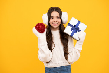 Teenager child girl holding present box isolated over yellow studio background. Present, greeting and gifting concept. New Year or Christmas holiday concept.