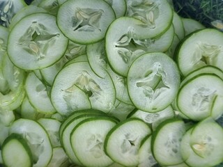 Fresh cucumbers are thinly sliced to prepare them for cooking.