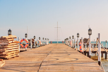 Obraz premium Wooden sea pier in sun lights at the sandy beach